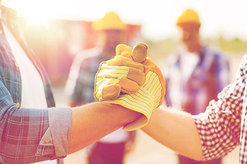 A handshake, both people are wearing construction gloves